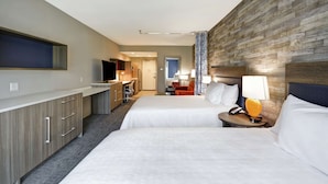 Une chambre d’hôtel avec deux lits, une télévision, un bureau et une salle de bain à l’arrière-plan.