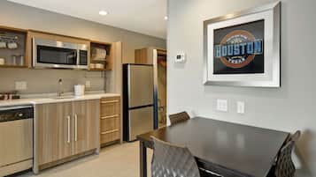 A modern kitchen with stainless steel appliances, wooden cabinets, and a dining area with a table and chairs.