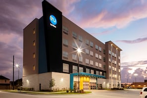 A modern hotel building with a prominent 'tru by Hilton' sign, multiple floors, and a well-lit entrance. - Tru by Hilton Cypress Houston (Cypress)