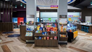 Zona comercial abierta las 24 horas con exhibición de aperitivos y bebidas, una barra de desayuno y una sección de productos locales.