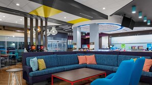 Un espacio lounge moderno con un sofá azul, una mesa de centro con marco rojo y un sillón azul.