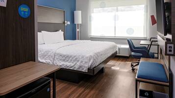 Habitación de hotel con cama, escritorio, silla y ventana con persianas.