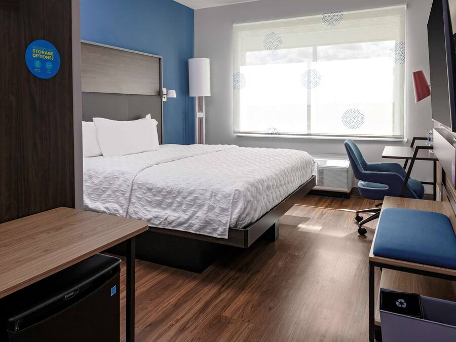Ein Hotelzimmer mit Bett, Schreibtisch, Stuhl und einem Fenster mit Jalousien.