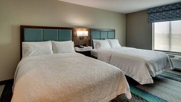 A hotel room with two beds, a nightstand, a lamp, and a large window.