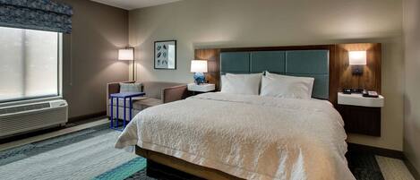 A hotel room with a large bed, bedside lamps, a desk, and a window with a view.