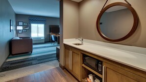 Un baño moderno con un espejo grande, armarios de madera y un microondas integrado.