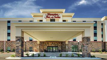 A Hampton Inn & Suites with a stone facade, large entrance, and covered parking area.