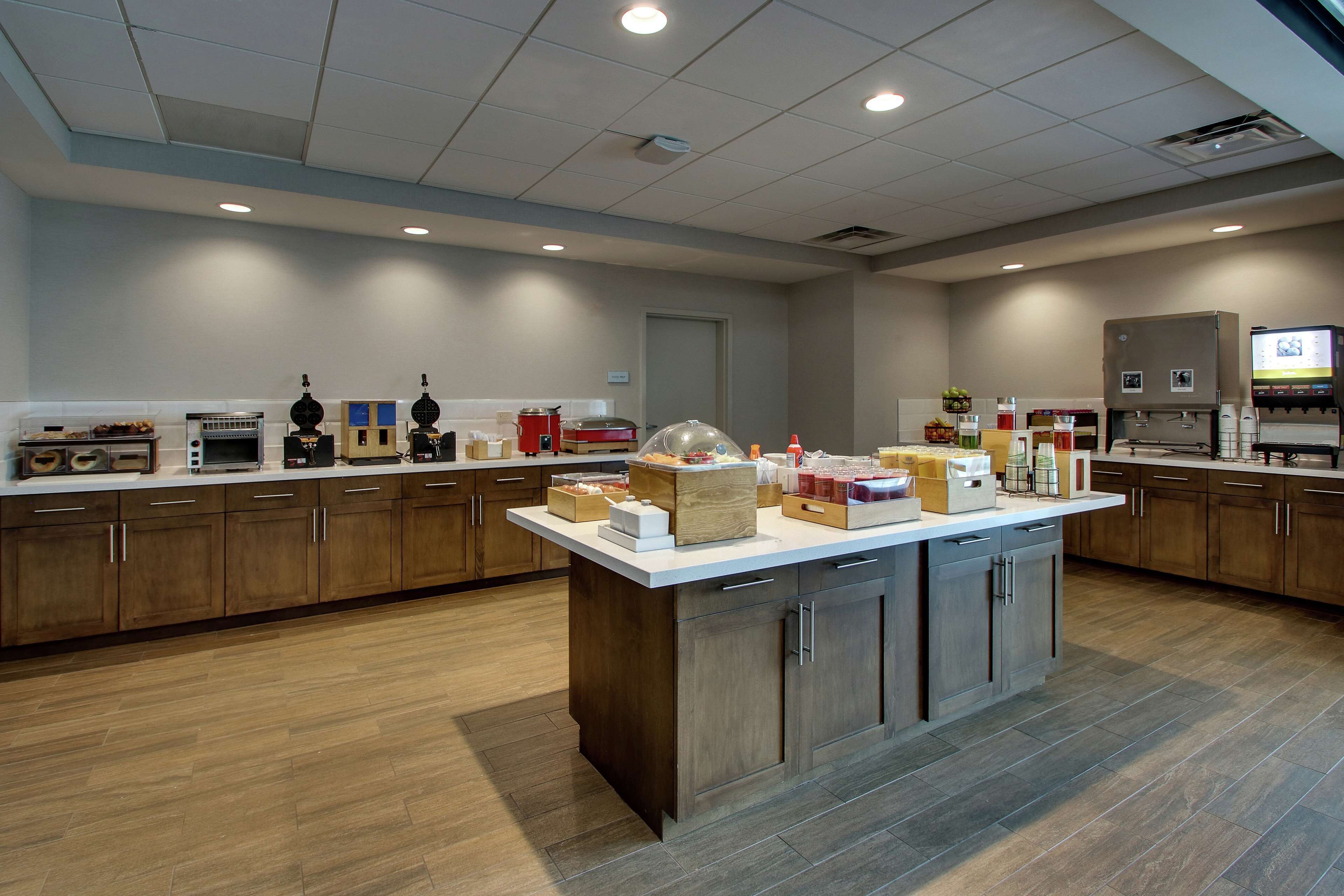 Een moderne keuken met houten kastjes, een centraal eiland en diverse apparaten.