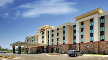 A hotel with a modern design, featuring a covered entrance and a parking lot.
