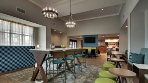 Un moderno vestíbulo de hotel con área de bar, asientos y una pantalla de televisión.