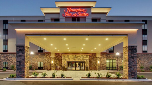 Un Hampton Inn & Suites con fachada de piedra, amplia entrada y exterior bien iluminado.