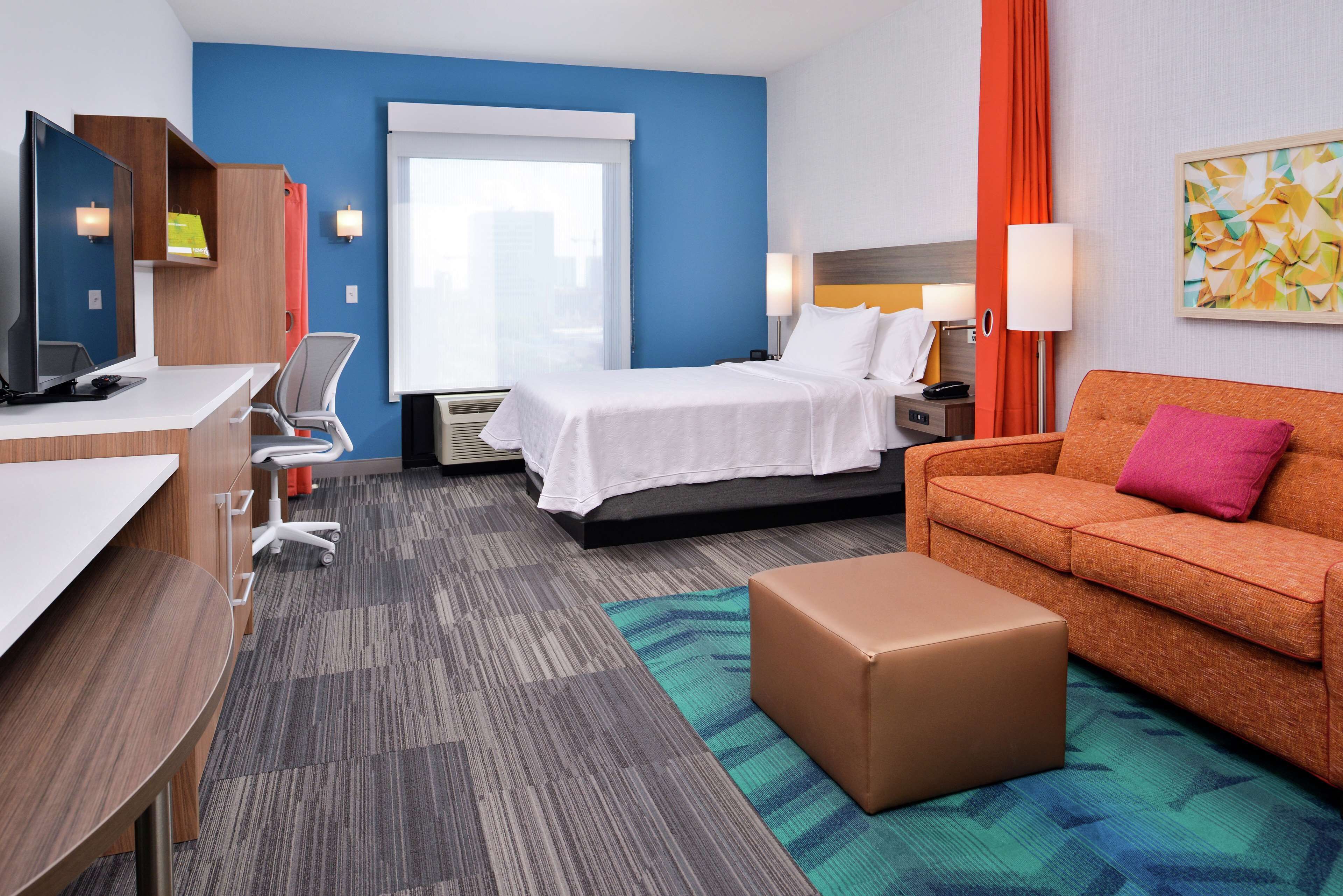 Una habitación de hotel con cama, escritorio, sillón, sofá y una mesita.