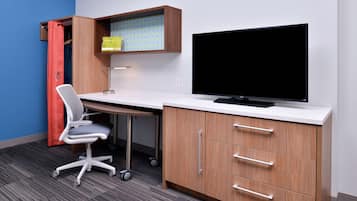 A modern office space with a desk, chair, television, and storage cabinets.