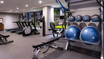 A gym with treadmills, a bench press, and a rack of blue medicine balls.