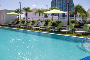 Una piscina al aire libre, sombrillas, tumbonas