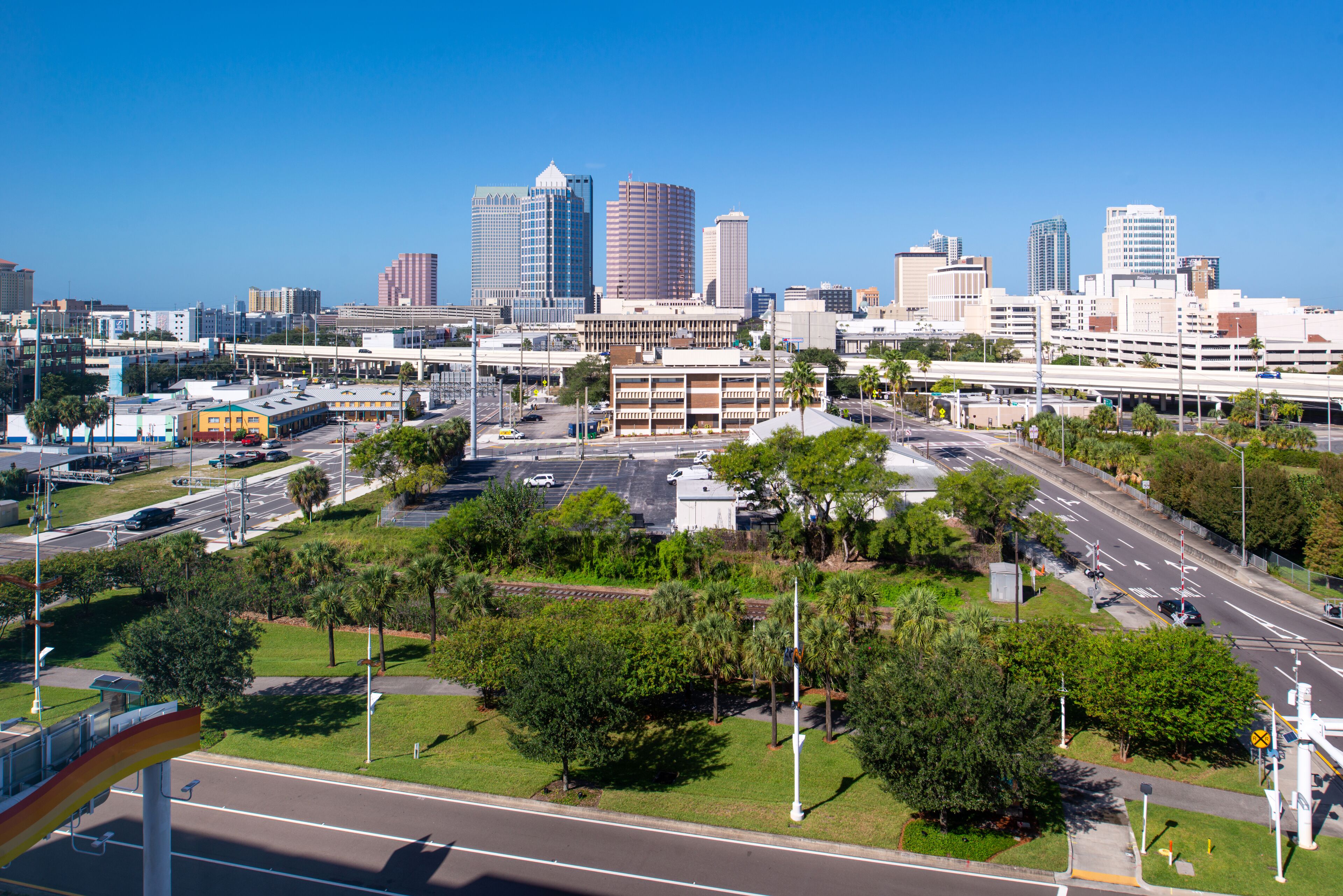 A cityscape with modern buildings, a parking lot, and green spaces.