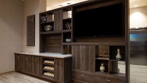 A modern living room with a built-in entertainment system, wooden cabinetry, and a flat-screen TV.