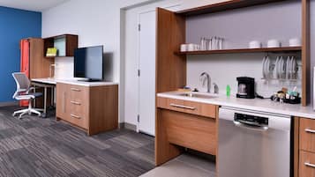 A modern kitchen with a built-in dishwasher, a flat-screen TV, and a coffee maker.
