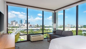 Une chambre d’hôtel avec une grande fenêtre, un lit, un bureau et une chaise.