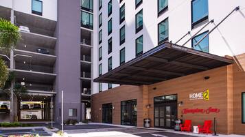A modern hotel entrance with a covered waiting area, guest registration, and a clear sign indicating a 13-00 clearance.