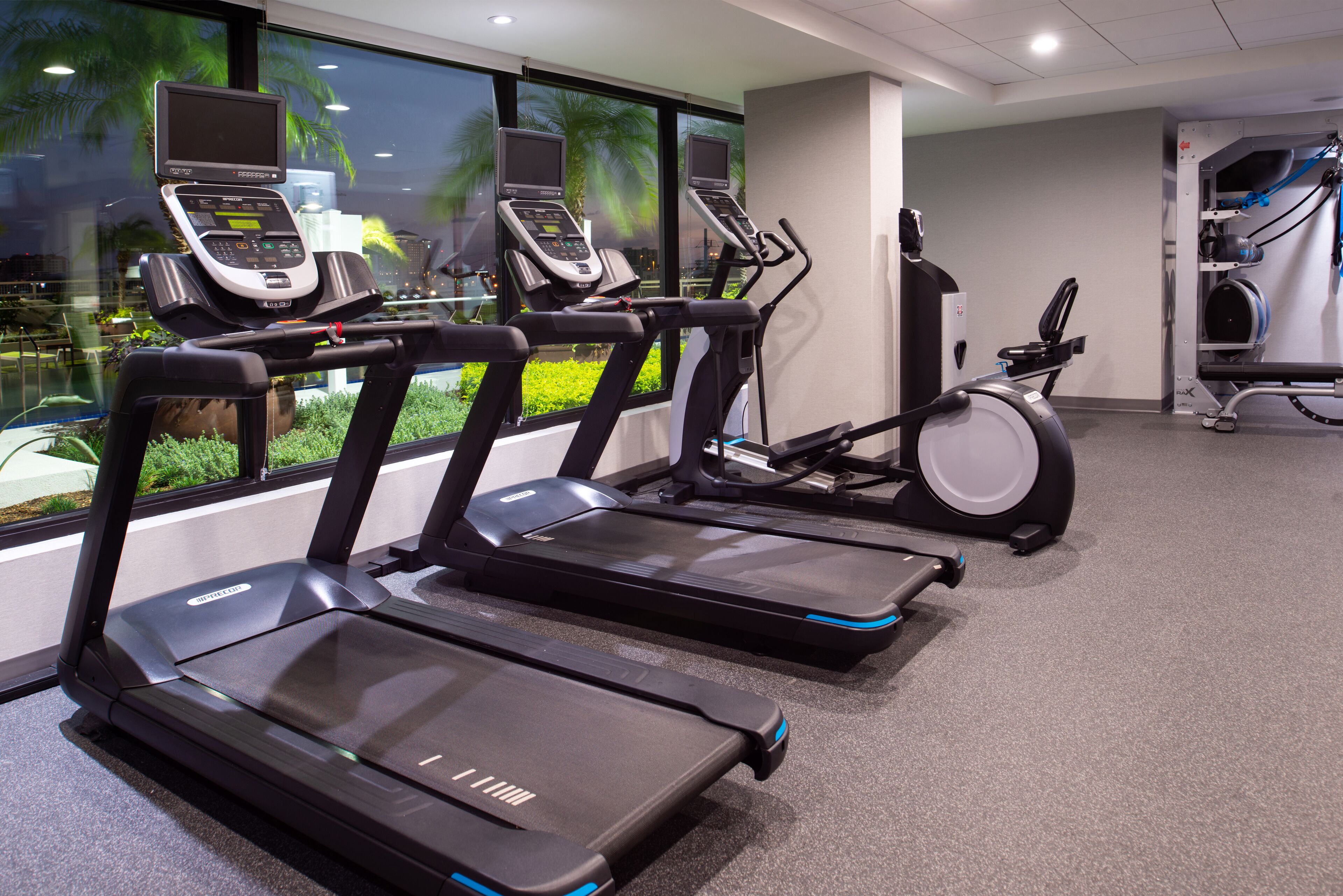 Un gimnasio con cintas de correr, bicicletas estáticas y equipo de ejercicio.