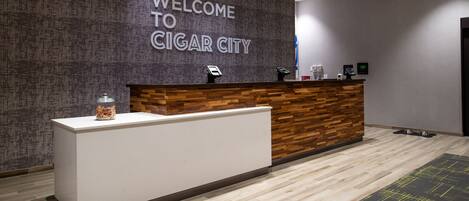 Una recepción con un cartel que dice "WELCOME TO CIGAR CITY", una pared de acento de madera y un diseño moderno.