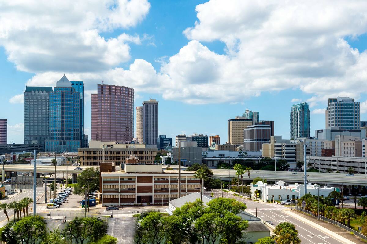 A cityscape with modern high-rise buildings, a parking lot, and a clear blue sky.