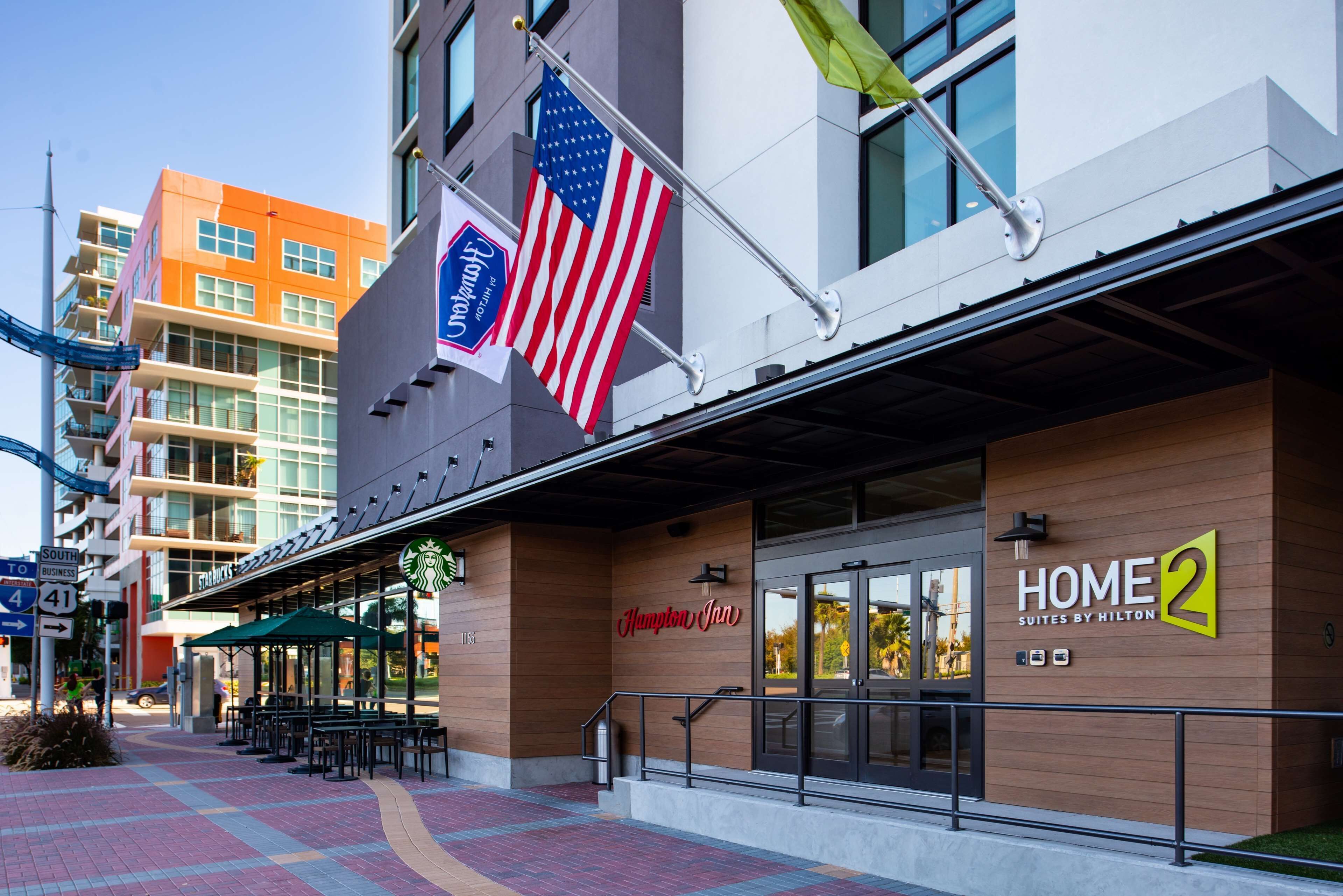 A hotel with a modern facade, a Starbucks sign, and an American flag.