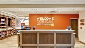 A reception desk with a "Welcome to the Sun Set State" sign, a counter, and a security camera.
