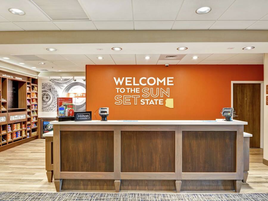 A reception desk with a "Welcome to the Sun Set State" sign, a counter, and a security camera.