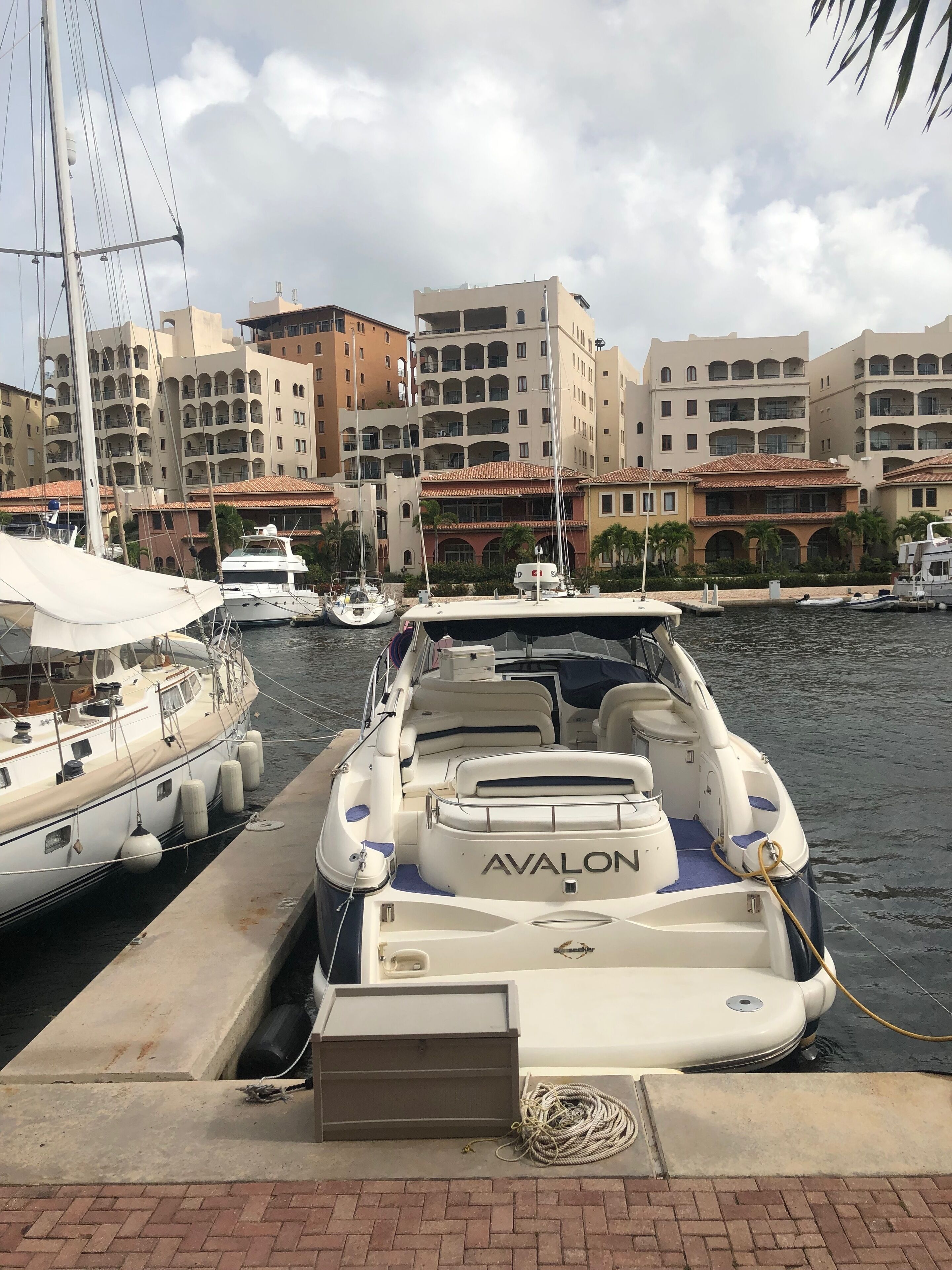 A marina with boats docked, a building with balconies, and a clear sky.