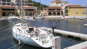 Un port de plaisance où sont amarrés plusieurs bateaux, un immeuble doté de nombreux balcons et un ciel dégagé.