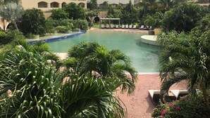 Un hôtel doté de nombreux balcons, d’une piscine et d’une végétation luxuriante.