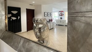 Un salon moderne avec une grande table basse en verre, un canapé blanc et une œuvre d’art encadrée accrochée au mur.