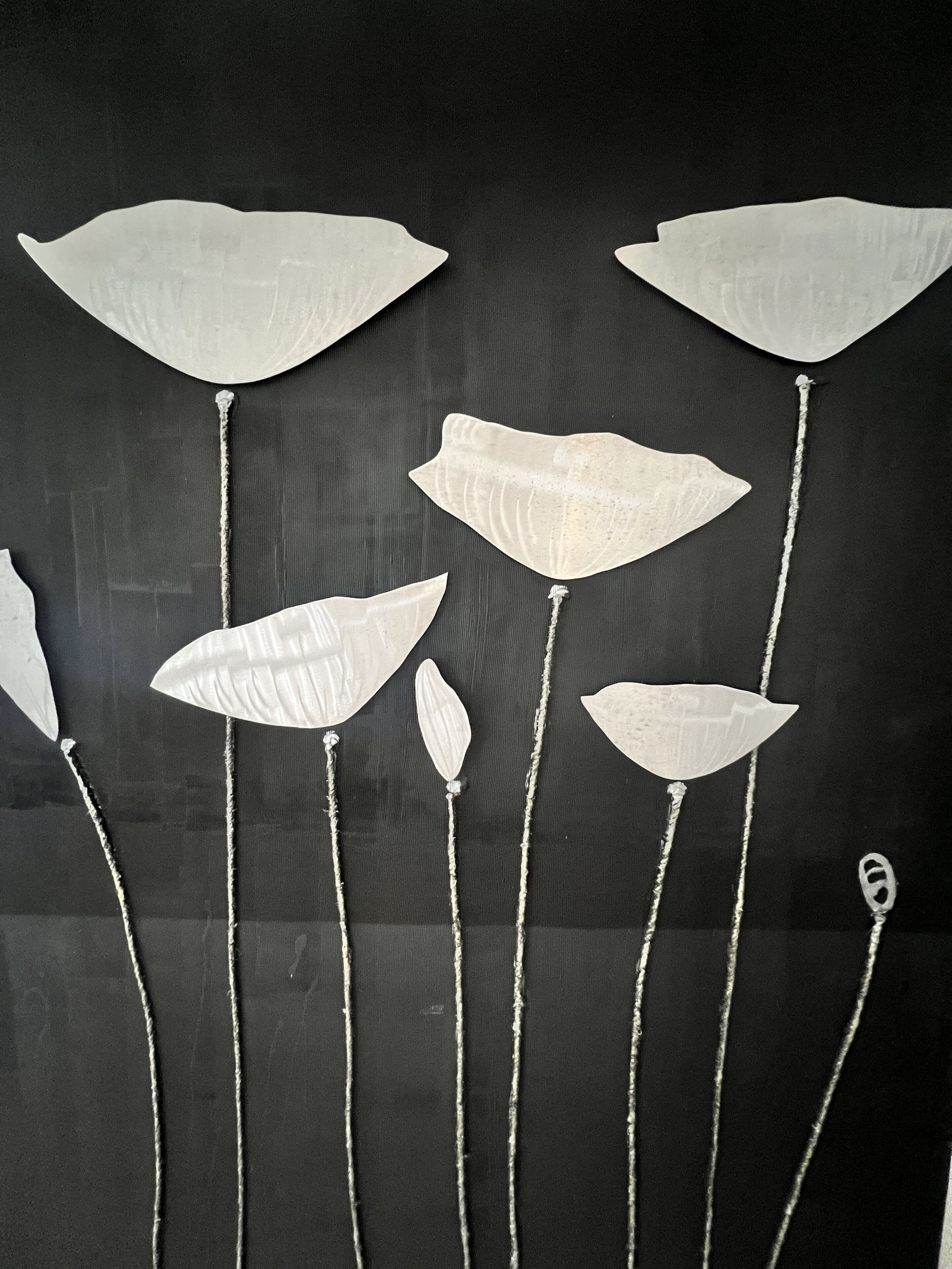 Una pared con una serie de adornos blancos con forma de hoja colgados de cuerdas.