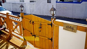 A wooden gate with two lanterns on top, a wooden bench, and a sign with the number 1865. - Yours Guesthouse (Tongyeong)