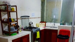 Cocina compacta con estufa a gas, un lavabo y una cesta de ropa roja.