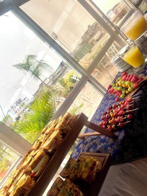 A breakfast buffet with sandwiches, fruit skewers, and a glass of orange juice. - Hotel House Center (Milagro)