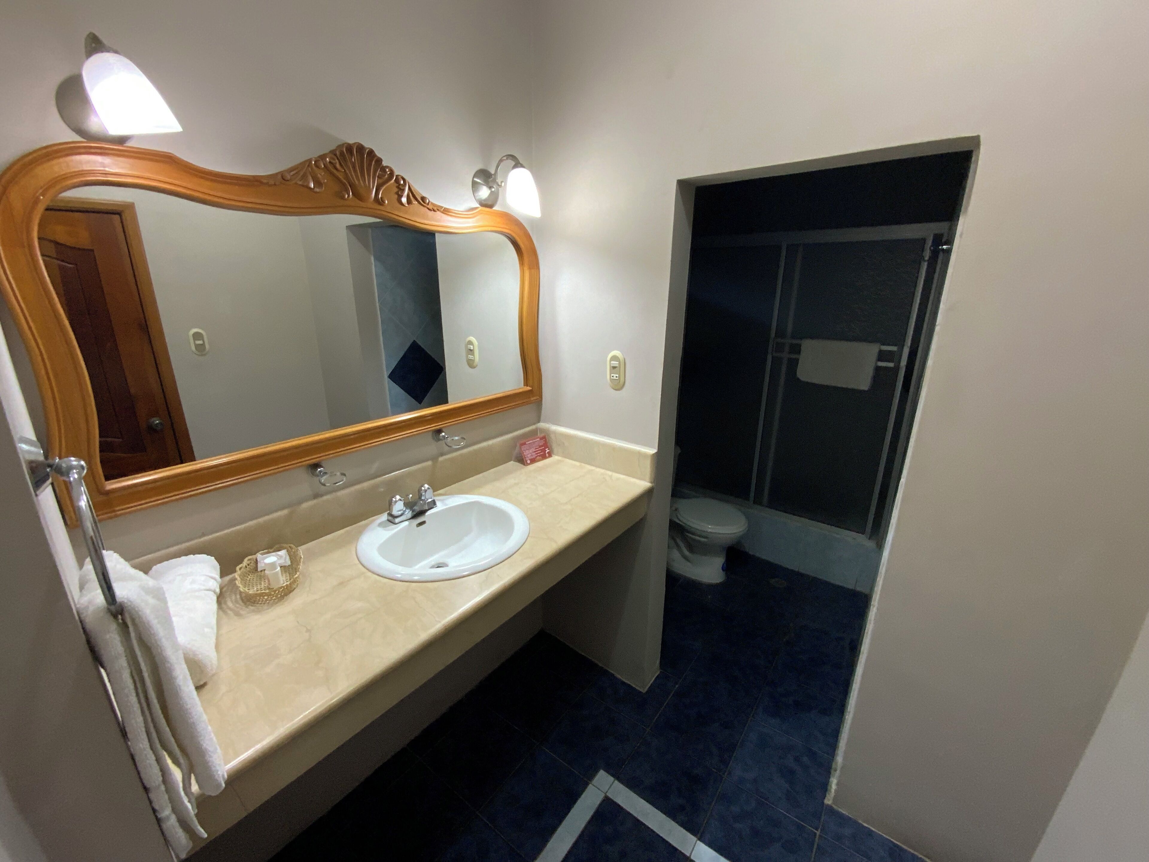 Un baño con lavamanos, espejo y mampara de ducha.
