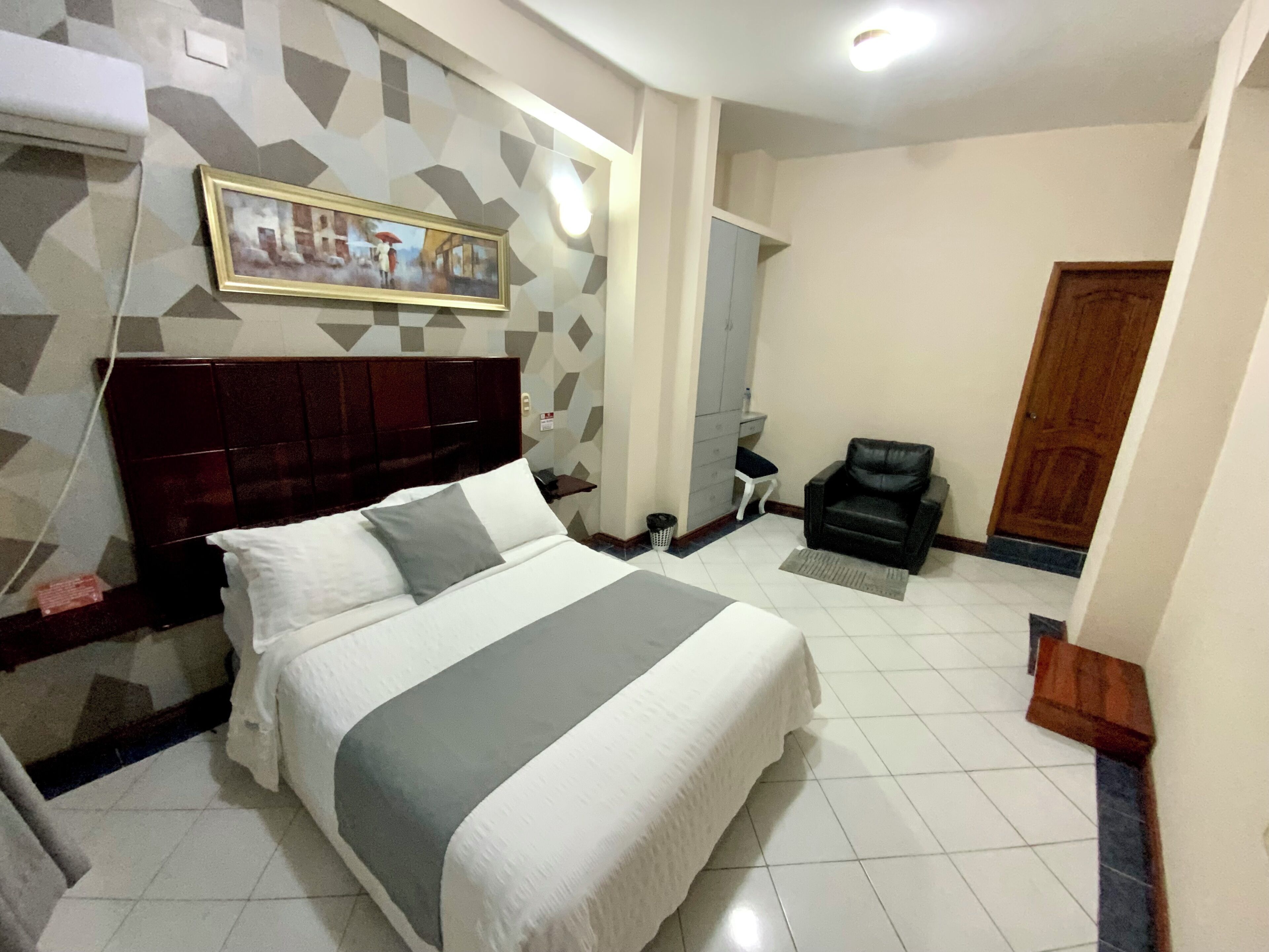 Quarto bem organizado com uma cama grande, uma cadeira, um guarda-roupa e uma porta.