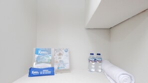 A bathroom with a towel, two bottles of water, and promotional materials on the counter. - Kamar Keluarga Bandara IV Syariah (Tangerang)