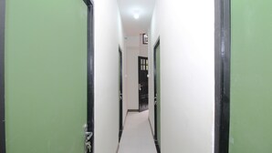 A narrow hallway with green doors on both sides and a white tiled floor. - Kamar Keluarga Bandara IV Syariah (Tangerang)