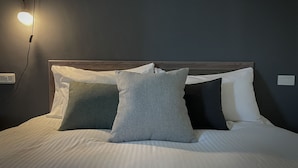 A neatly made bed with white linens and three pillows in shades of gray and white. - Eddie's House (Ruisui)