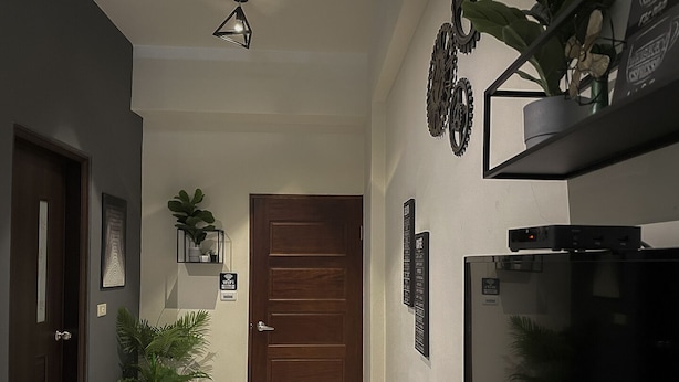 A hallway with a wooden door, a small table with plants, a wall-mounted shelf with decorative items, and a sign indicating Wi-Fi availability. - Eddie's House (Ruisui)