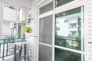 A modern hotel room with white tiled walls, a large window with a view of another building, and a water heater on the floor. - Eddie's House (Ruisui)