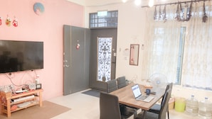 A dining area with a table, chairs, a laptop, and a TV. - Eddie's House (Ruisui)
