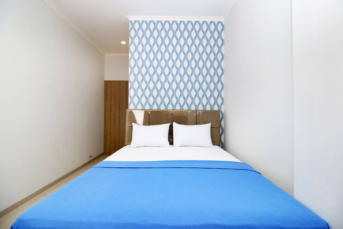 Ein Schlafzimmer mit einem Bett, einer Holztür und einer Wand mit Muster.