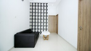 Un intérieur moderne avec un canapé noir, une table ronde blanche et un mur orné de motifs.