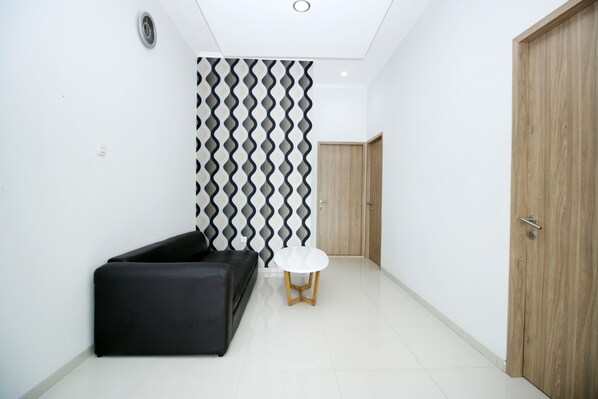 A modern interior with a black sofa, a white round table, and a patterned wall.