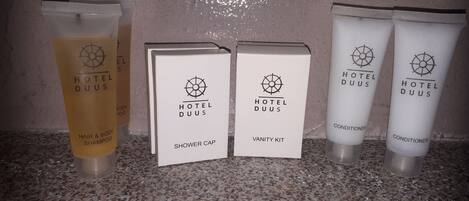 A display of Hotel Duus products including hair and body shampoo, shower cap, vanity kit, and conditioner.